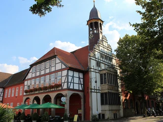 Historisch stadhuis van Nienburg met opvallende klokkentoren, vakwerkgevel en kleurrijke buitencatering.