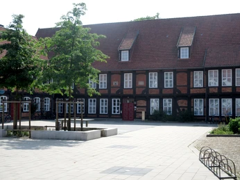 Fresenhof Historisches Fachwerkgebäude Fresenhof mit Dachschindeln, weiße Fensterrahmen, markant rotes Tor.Historic half-timbered building Fresenhof with roof shingles, white window frames, striking red gate.Historisk bindingsværksbygning Fresenhof med tagspån, hvide vinduesrammer, markant rød port.Historisch vakwerkgebouw Fresenhof met dakschindels, witte raamkozijnen, opvallende rode poort.