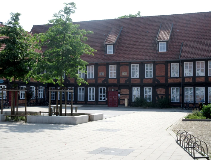 Fresenhof Historisches Fachwerkgebäude Fresenhof mit Dachschindeln, weiße Fensterrahmen, markant rotes Tor.Historic half-timbered building Fresenhof with roof shingles, white window frames, striking red gate.Historisk bindingsværksbygning Fresenhof med tagspån, hvide vinduesrammer, markant rød port.Historisch vakwerkgebouw Fresenhof met dakschindels, witte raamkozijnen, opvallende rode poort.