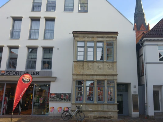 Renaissance-Erker mit filigranen Reliefs an einem modernen Geschäftsgebäude in urbaner Umgebung.