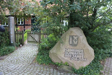 Robberts Huus Vor einem Backsteinhaus steht ein geschmückter Stein zum 800-jährigen Bestehen der Gemeinde Schwarme.
