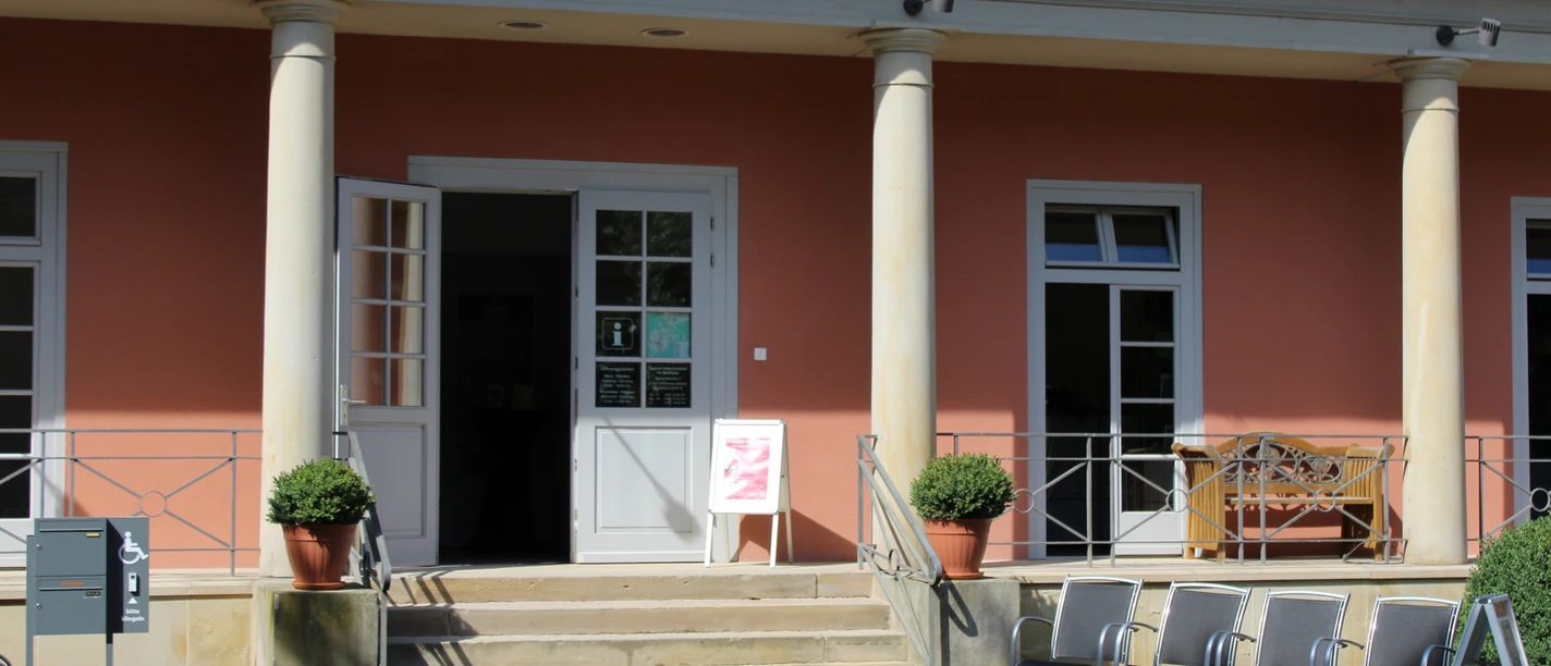 Tourist-Info Romantik Bad Rehburg Turistinformation i Bad Rehburg med åben indgangsdør og trappe, omgivet af søjler.