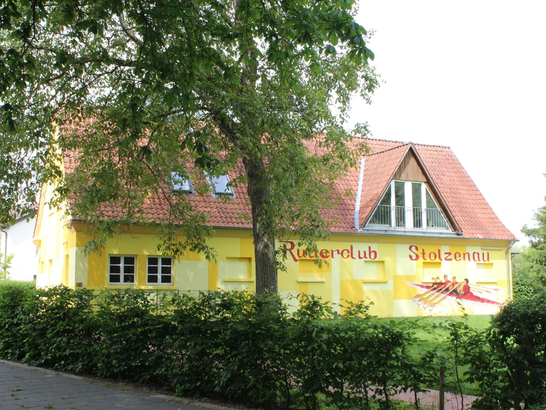 Ein gelb getünchtes Gebäude mit der Aufschrift "Ruderclub Stolzenau" und einem gemalten Ruderboot.