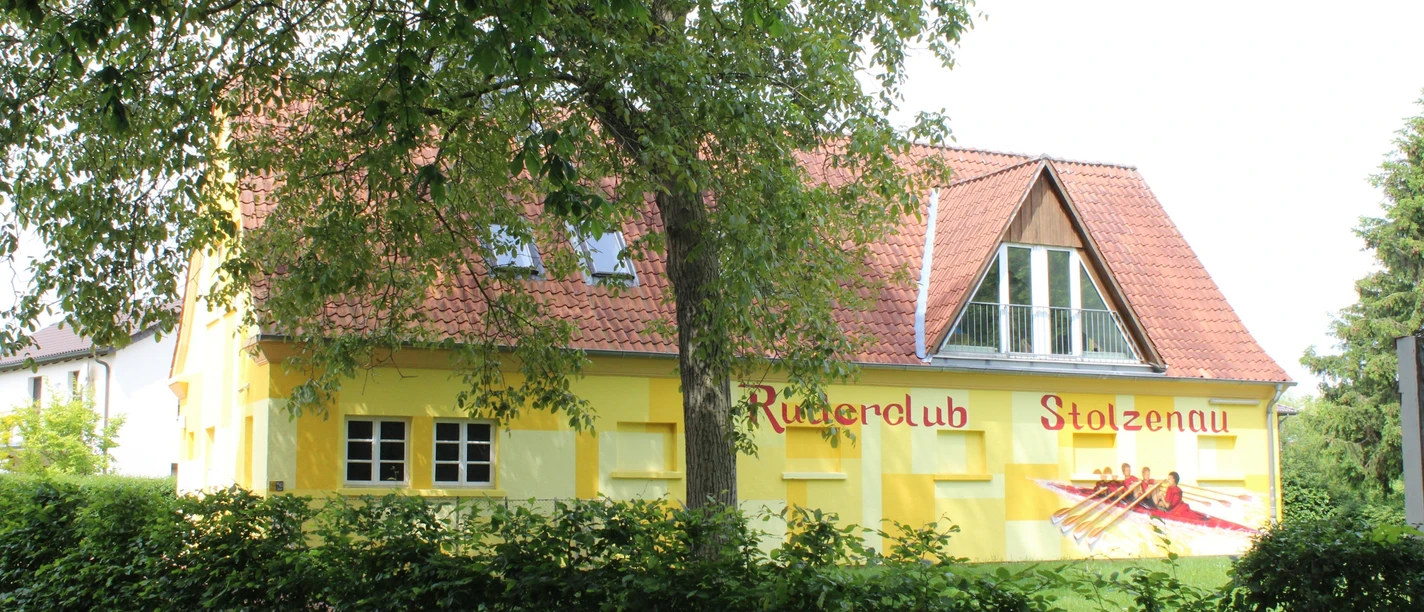 Ein gelb getünchtes Gebäude mit der Aufschrift "Ruderclub Stolzenau" und einem gemalten Ruderboot.