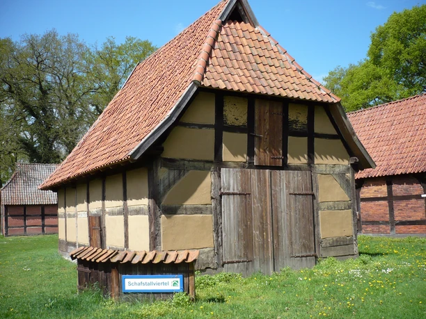 Schafstallviertel Hülsen Traditioneller Fachwerkschafstall mit rotem Ziegeldach, umgeben von grüner Wiese im Schafstallviertel Hülsen.