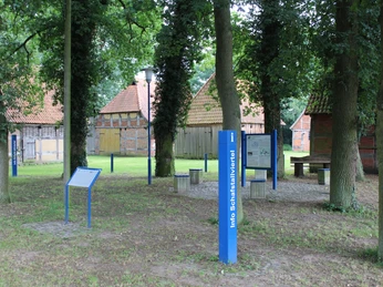 Inmitten großer Bäume befinden sich historische Schafställe und Infotafeln im Schafstallviertel.