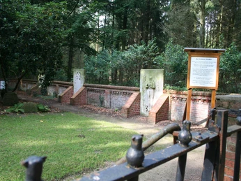 Friedhof Schloss Eickhof Eine friedvolle, von Bäumen umrahmte Grabstätte mit roten Backsteinmauern und historischen Grabsteinen.