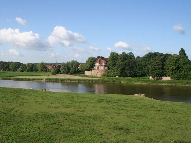 Schloss Petershagen an der Weser, umgeben von grünen Wiesen und einem klaren blauen Himmel.
