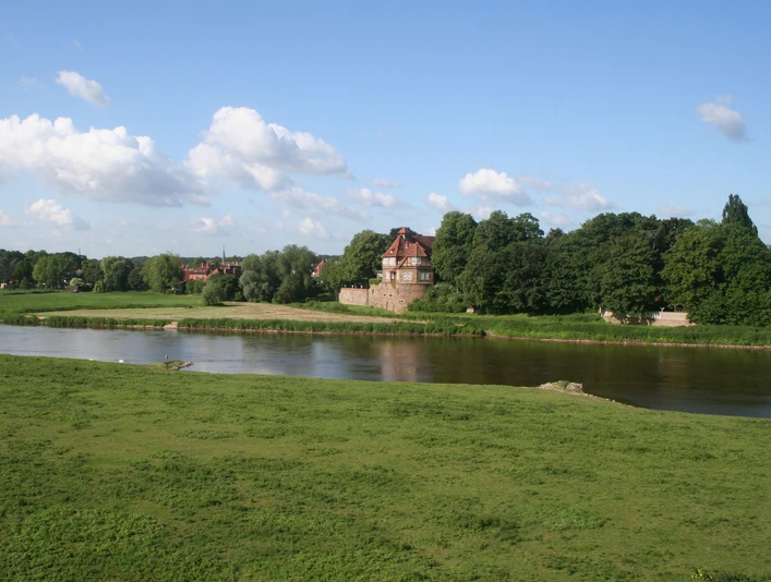 Schloss Petershagen an der Weser, umgeben von grünen Wiesen und einem klaren blauen Himmel.
