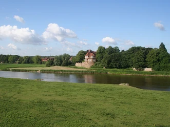 Schloss Petershagen Schloss Petershagen an der Weser, umgeben von grünen Wiesen und einem klaren blauen Himmel.