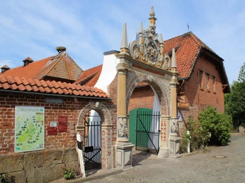 Weserrenaissance-Tor seitlich Seitlich aufgenommene Perspektive eines kunstvollen Weserrenaissance-Tors mit rotem Backsteingebäude.