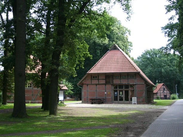 Historische Ziegelsteinscheunen mit Fachwerk-Elementen im Grünen, umgeben von Bäumen und Natur.