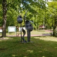 Skulptur "Beeren von Katharina Franck" Skulptur aus Metall, zeigt stilisierte Beeren in einem Park mit Bäumen und Informationstafel.