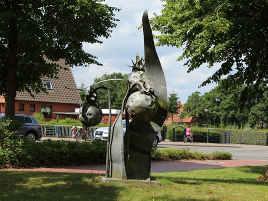 Skulptur "Beeren von Katharina Franck" Skulptur aus Metall zeigt überdimensionale Beeren an einem grünen Platz unter schattenspendenden Bäumen.