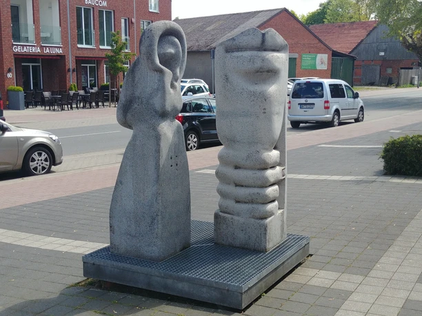 Zwei moderne Steinskulpturen symbolisieren den Hör- und Geschmacksinn auf einem öffentlichen Platz.