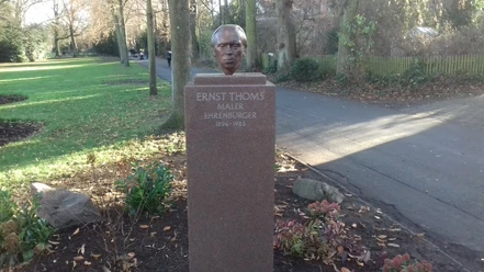 Bronzeskulptur von Ernst Thoms auf einem Sockel im Grünen, gewidmet als Maler und Ehrenbürger.