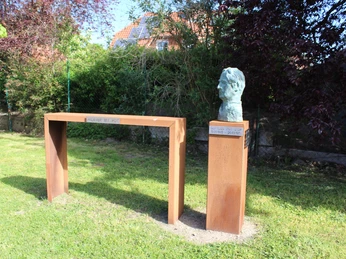 Skulptur einer bronzenen Kopf-Büste von Gottlieb Pot d'Or, auf einem Metallpodest im Grünen platziert.