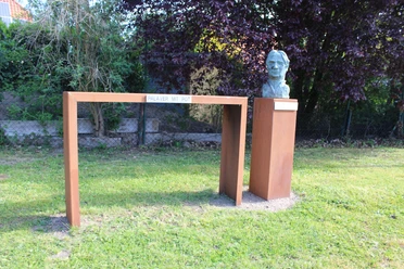 Skulptur Gottlieb Pot d'Or Bronzene Büste von Gottlieb Pot d'Or auf Steinsockel, verbunden durch moderne Stahlkonstruktion im Grünen.