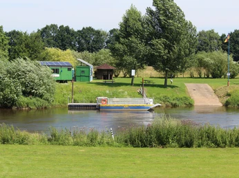 Solare Fähre überquert die Aller, umgeben von grünem Uferbereich und Bäumen, Vogelperspektive.