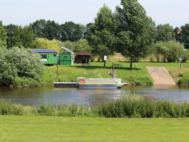 Solare Allerfähre Westen Solare Fähre überquert die Aller, umgeben von grünem Uferbereich und Bäumen, Vogelperspektive.