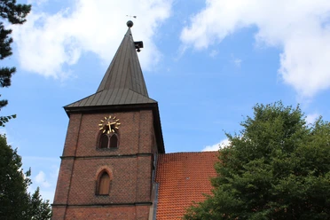 St. Aegidien-Kirche Rodewald Backsteinkirche mit markantem Kirchturm und Uhr in grüner Umgebung unter blauem Himmel.