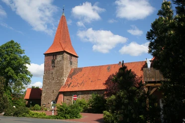 St.-Bartholomäus-Kirche in Balge St.-Bartholomäus-Kirche in Balge mit markantem rotem Backstein und spitzem Turm, umgeben von Bäumen.