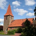 St.-Bartholomäus-Kirche in Balge St.-Bartholomäus-Kirche in Balge mit markantem rotem Backstein und spitzem Turm, umgeben von Bäumen.