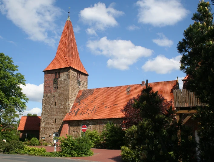 St.-Bartholomäus-Kirche in Balge St.-Bartholomäus-Kirche in Balge mit markantem rotem Backstein und spitzem Turm, umgeben von Bäumen.
