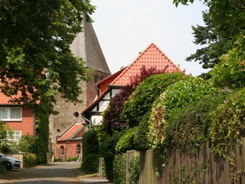 Clemenskirche Marklohe Die Clemenskirche Marklohe, umgeben von grünen Bäumen und Häusern, strahlt historische Würde aus.