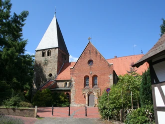 St.-Clemens-Romanus-Kirche in Marklohe, rot verklinkert mit markantem Kirchturm und grüner Umgebung.