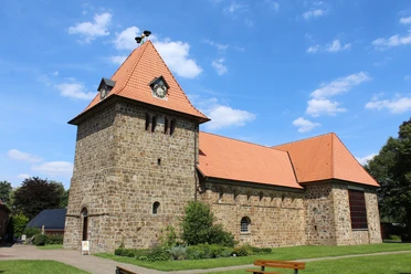 St.-Gangolf-Kirche in Wietzen Rundturm-Kirche aus Naturstein mit rotem Ziegeldach, umgeben von parkähnlicher Grünanlage.