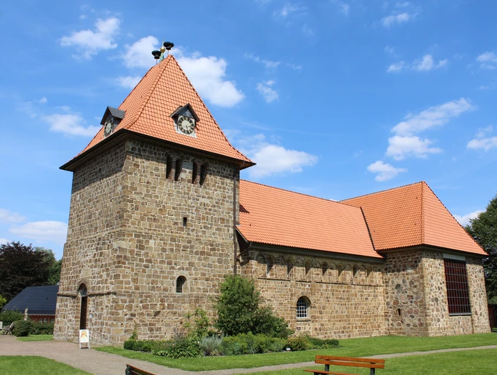 St.-Gangolf-Kirche in Wietzen Rundturm-Kirche aus Naturstein mit rotem Ziegeldach, umgeben von parkähnlicher Grünanlage.