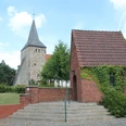 St. Dionysius-Kirche in Steimbke mit historischer Architektur, neben einem kleinen, efeubewachsenen Gebäude.