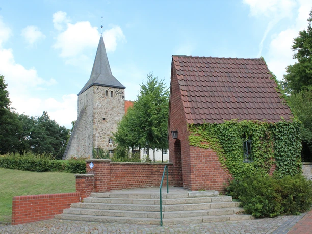 St. Dionysius-Kirche Steimbke St. Dionysius-Kirche in Steimbke mit historischer Architektur, neben einem kleinen, efeubewachsenen Gebäude.