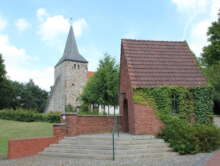 St. Dionysius-Kirche Steimbke St. Dionysius-Kirche in Steimbke mit historischer Architektur, neben einem kleinen, efeubewachsenen Gebäude.