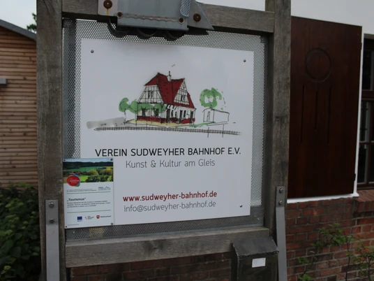 Sudweyher Bahnhof Schild Schild des Vereins Sudweyher Bahnhof e.V. mit gezeichnetem Gebäude und Kontaktinformationen.