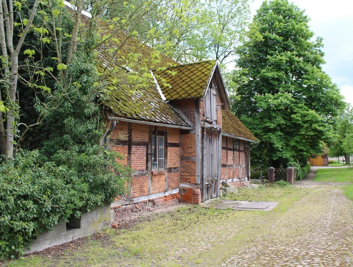 Wassermühle Heuermann Historische Wassermühle Heuermann aus rotem Backstein, umgeben von Bäumen, mit leicht bemoostem Dach.