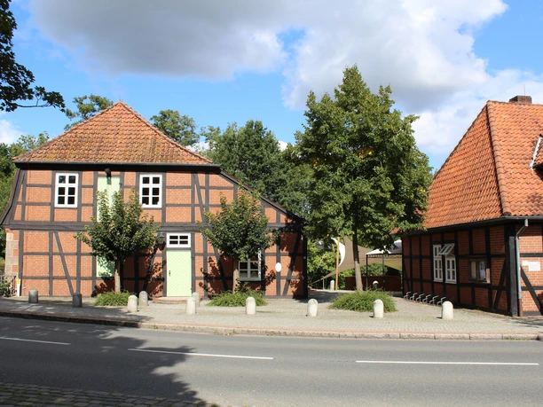 Historische Fachwerkgebäude der Wassermühle Sudweyhe an einer ruhigen Straße, umgeben von Bäumen.