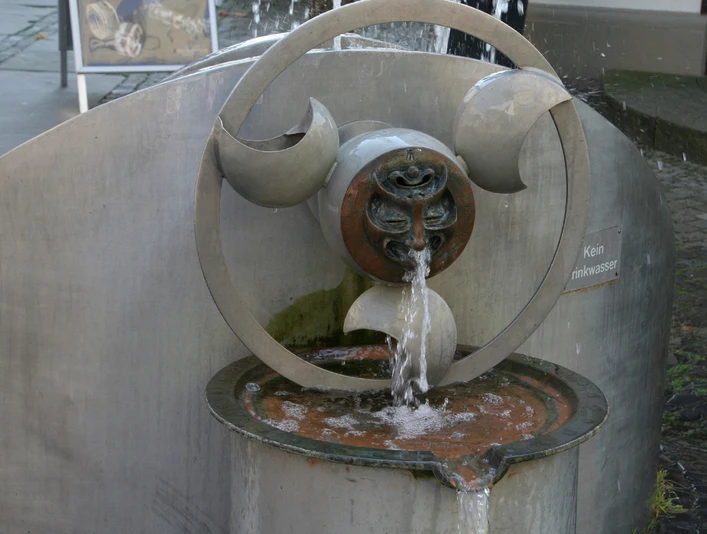 Moderner Wasserspielbrunnen aus Metall, künstlerisch gestaltet, sprudelndes Wasser und Details.