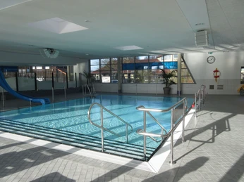 Nichtschwimmerbecken Ein Hallenbad mit einem Nichtschwimmerbecken, einer blauen Rutsche und viel natürlichem Licht.An indoor pool with a non-swimmer's pool, a blue slide and lots of natural light.En indendørs pool med et ikke-svømmebassin, en blå rutsjebane og masser af naturligt lys.Een binnenzwembad met een niet-zwemmersbad, een blauwe glijbaan en veel natuurlijk licht.