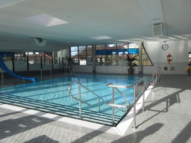 Nichtschwimmerbecken An indoor pool with a non-swimmer's pool, a blue slide and lots of natural light.
