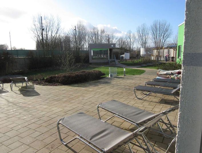Außenbereich mit Sauna Entspannungsbereich mit mehreren Sonnenliegen, Bäumen und einem kleinen Saunahaus im Hintergrund.Relaxation area with several sun loungers, trees and a small sauna house in the background.Afslapningsområde med flere liggestole, træer og et lille saunahus i baggrunden.Ontspanningsruimte met verschillende ligstoelen, bomen en een klein saunahuisje op de achtergrond.