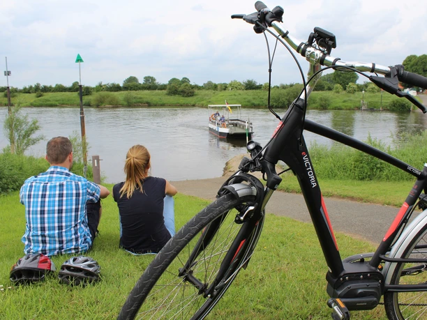 Weserfähre Gentsiet Hagen-Grinden - Ahsen-Oetzen Menschen genießen den Anblick einer vorbeifahrenden Weserfähre bei Ahsen-Oetzen, Fahrräder im Vordergrund.