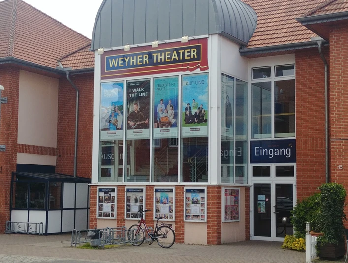Weyher Theater Weyher Theater mit roter Backsteinfassade, Plakaten aktueller Stücke und Eingangsbereich.