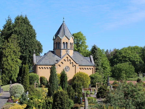 Backstein-Mausoleum mit sechseckigem Turm, umgeben von gepflegten Gärten und grünen Bäumen.