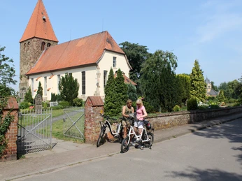 Willehadikirche in Eystrup Zwei Radfahrer pausieren vor der historischen Willehadikirche in Eystrup mit ihren markanten Ziegeln.