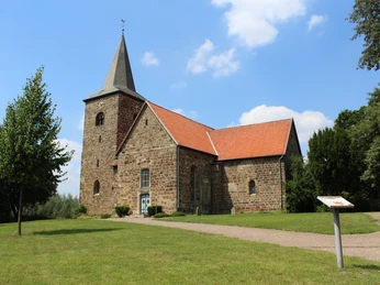 Kirche Windheim Die Kirche in Windheim mit rotem Ziegeldach, umgeben von grünem Rasen und blauem Himmel.