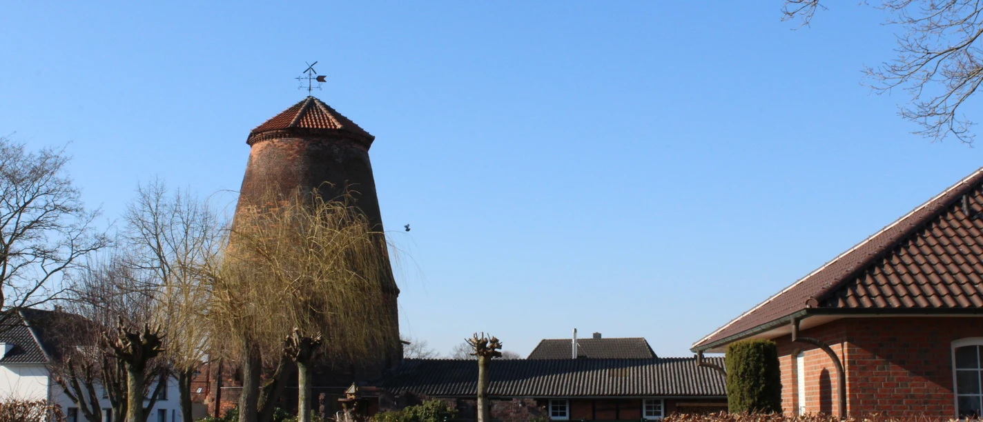 Historische Windmühle mit Backsteingebäuden im strahlenden Sonnenschein eines klaren Tages.