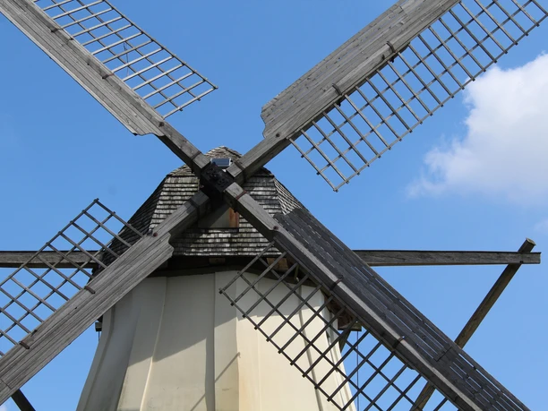 Windmühle Großenheerse Eine historische Windmühle mit markanten Holzflügeln vor einem klaren blauen Himmel in Großenheerse.