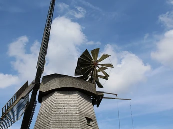 Windmühle Meßlingen Historische Windmühle mit hölzernem Schindeldach und großen Flügeln vor blauem Himmel mit Wolken.